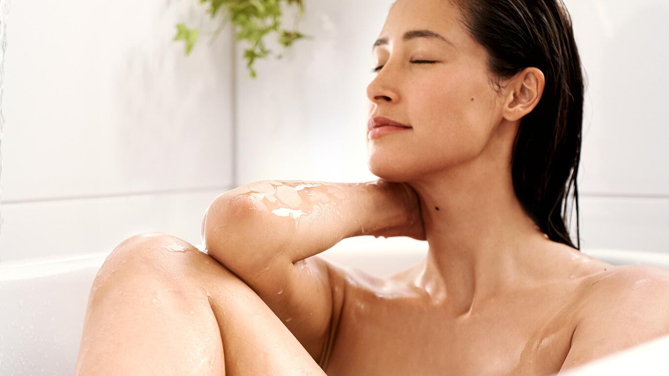 Dark haired woman relaxing in the bathtub.