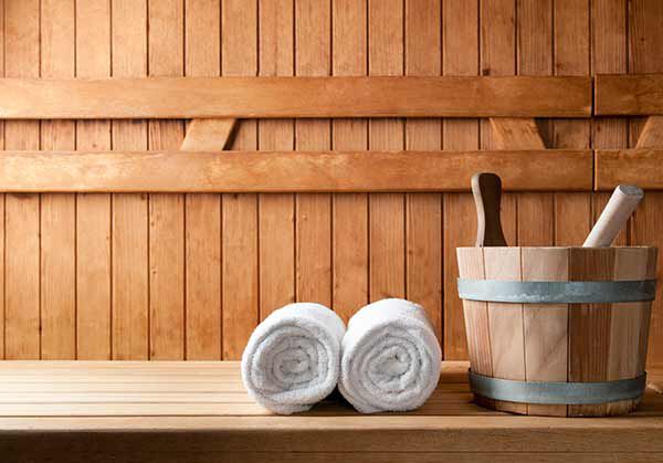 Sauna-Equipment und Handtücher in einer Sauna. 