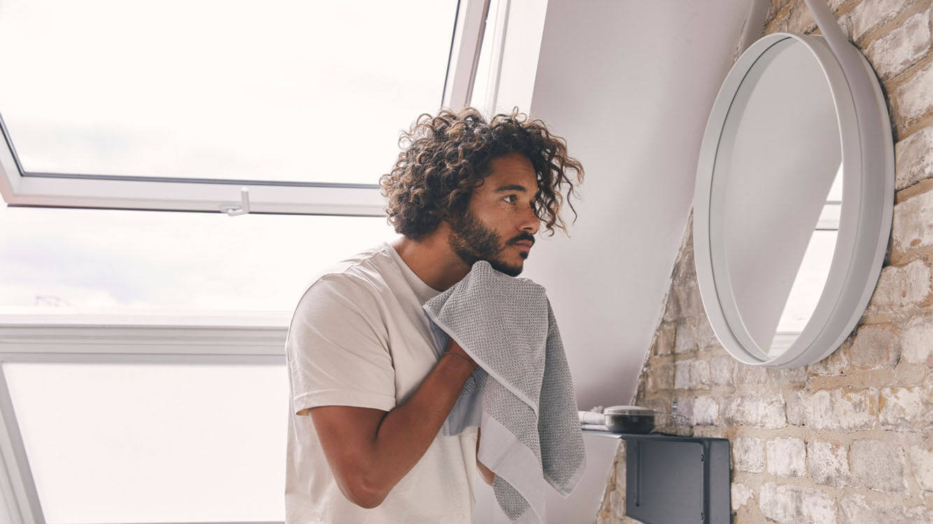 Mann  trocknet sich im Badezimmer mit einem Handtuch ab.