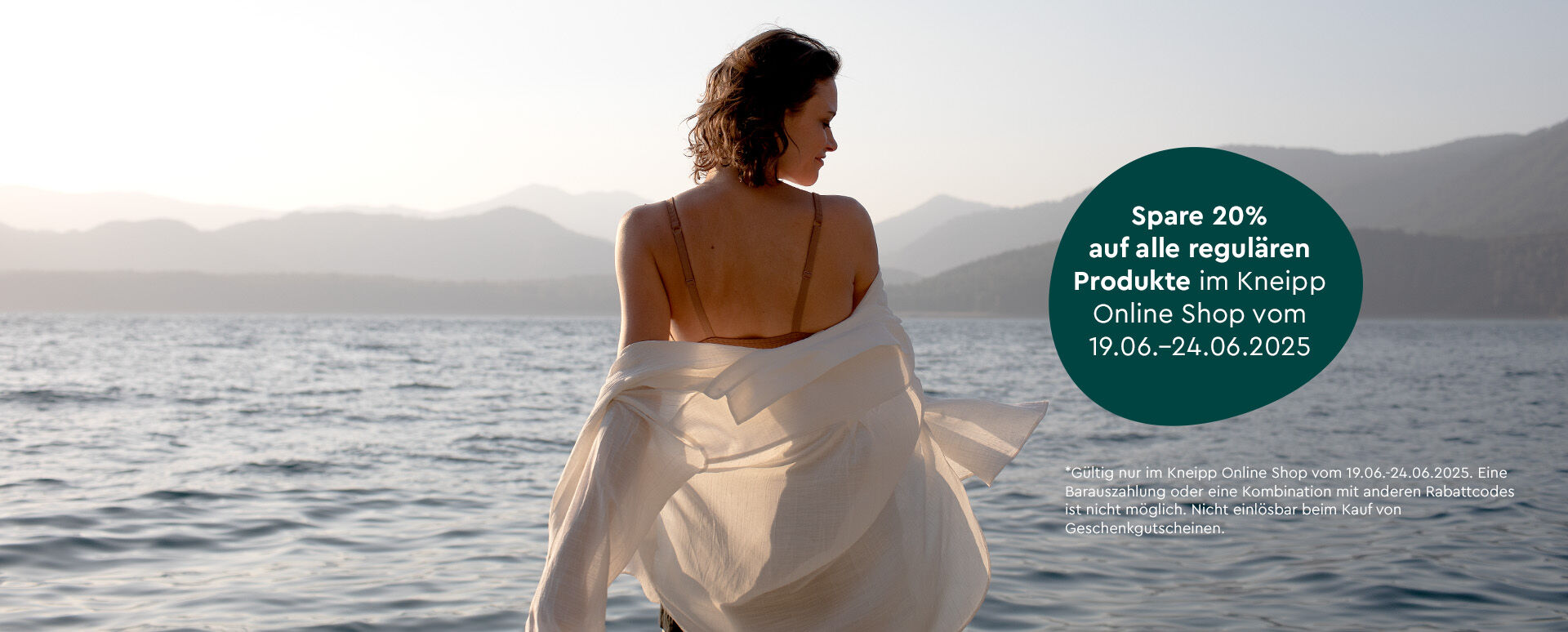 Frau steht im Meer im sommerlichen Badeoutfit.