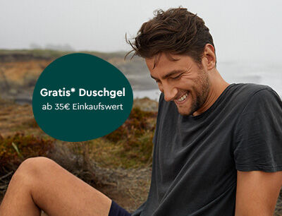 Mann sitzt am Strand im Sand.