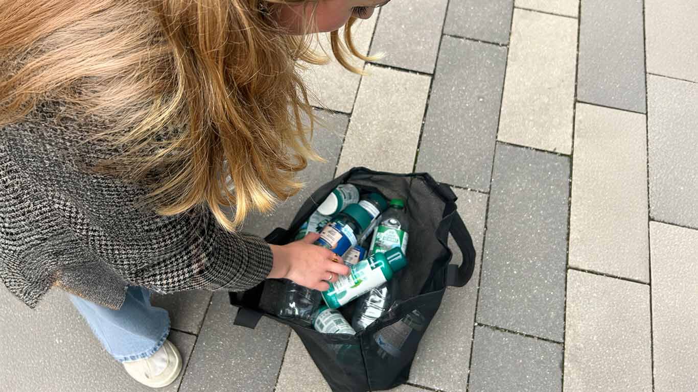 Frau beugt sich über eine Tasche mit Pfandflaschen und leeren Kneipp Verpackungen.