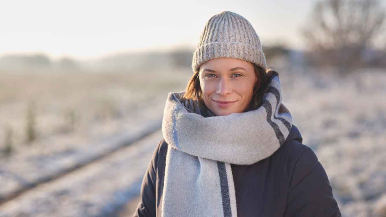Frau in Winterkleidung in verschneiter Natur.