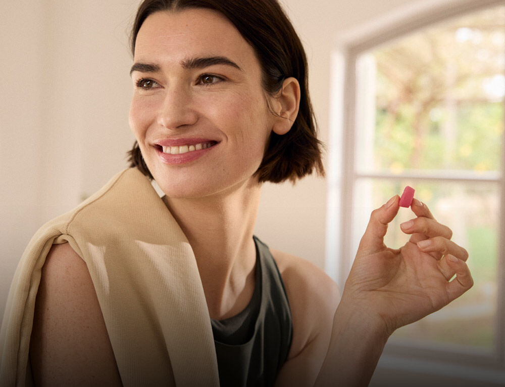 Frau mit einem Nahrungserg&auml;nzungsmittel Gummi in der Hand.