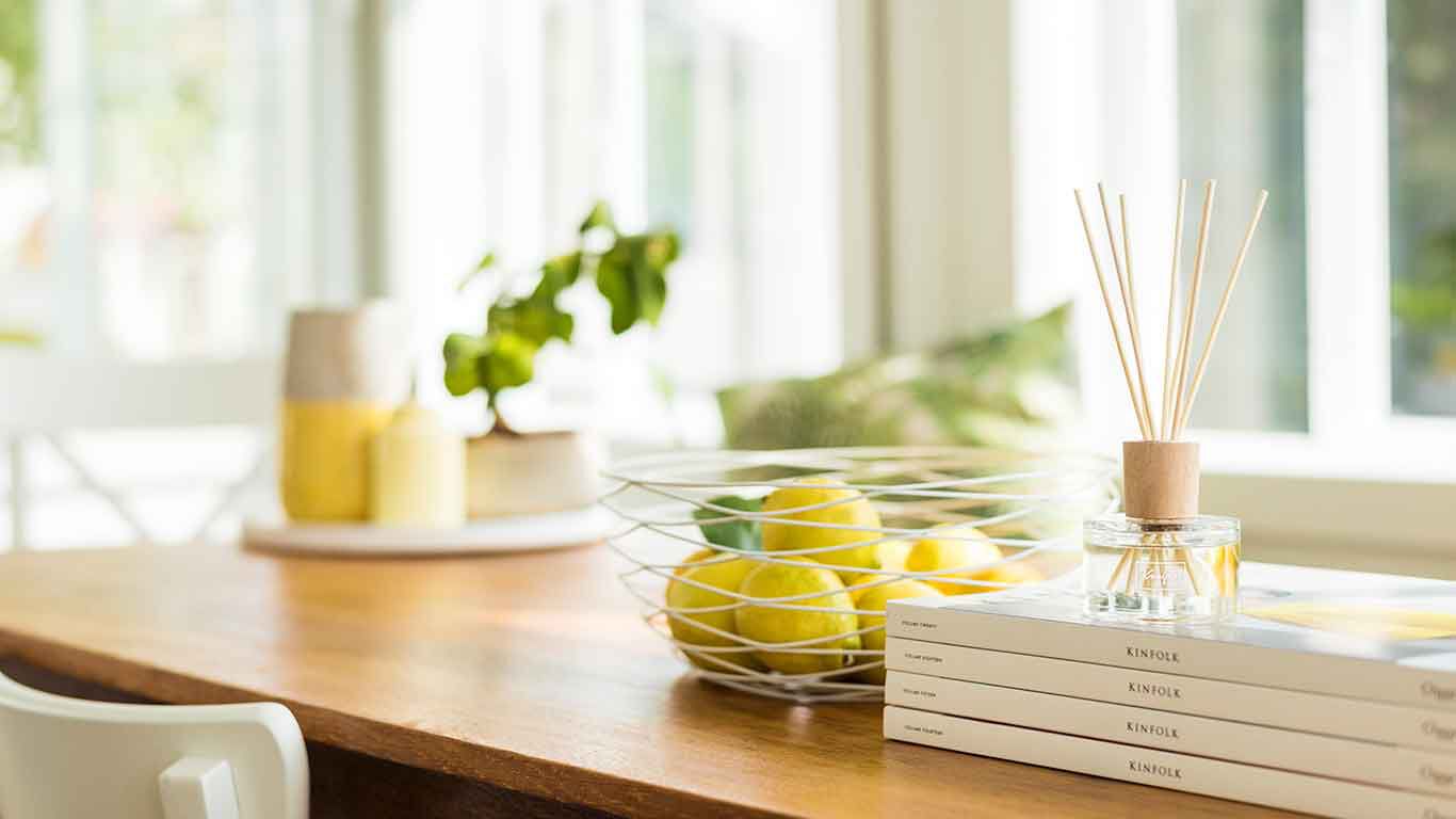 Kneipp Duftstäbchen auf Holz-Küchentisch neben einer Schale mit Zitronen.