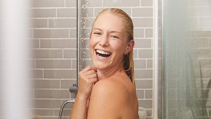 Fröhliche Frau in der Dusche.