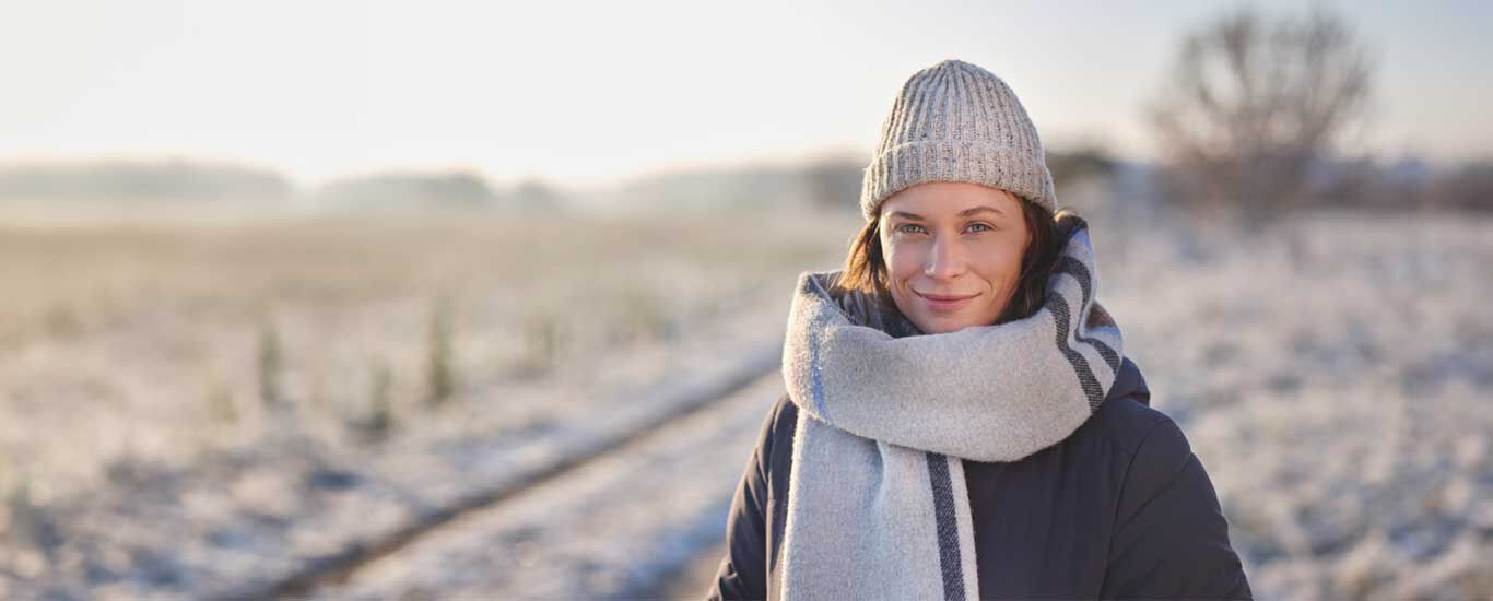 Frau in Winterkleidung in verschneiter Natur.
