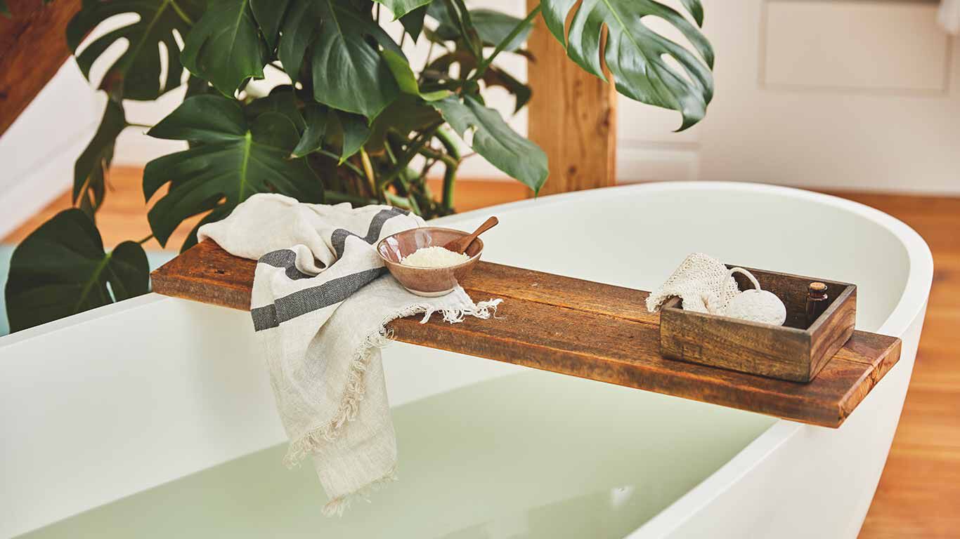 Badewanne mit Holzbrett und Badeutensilien.