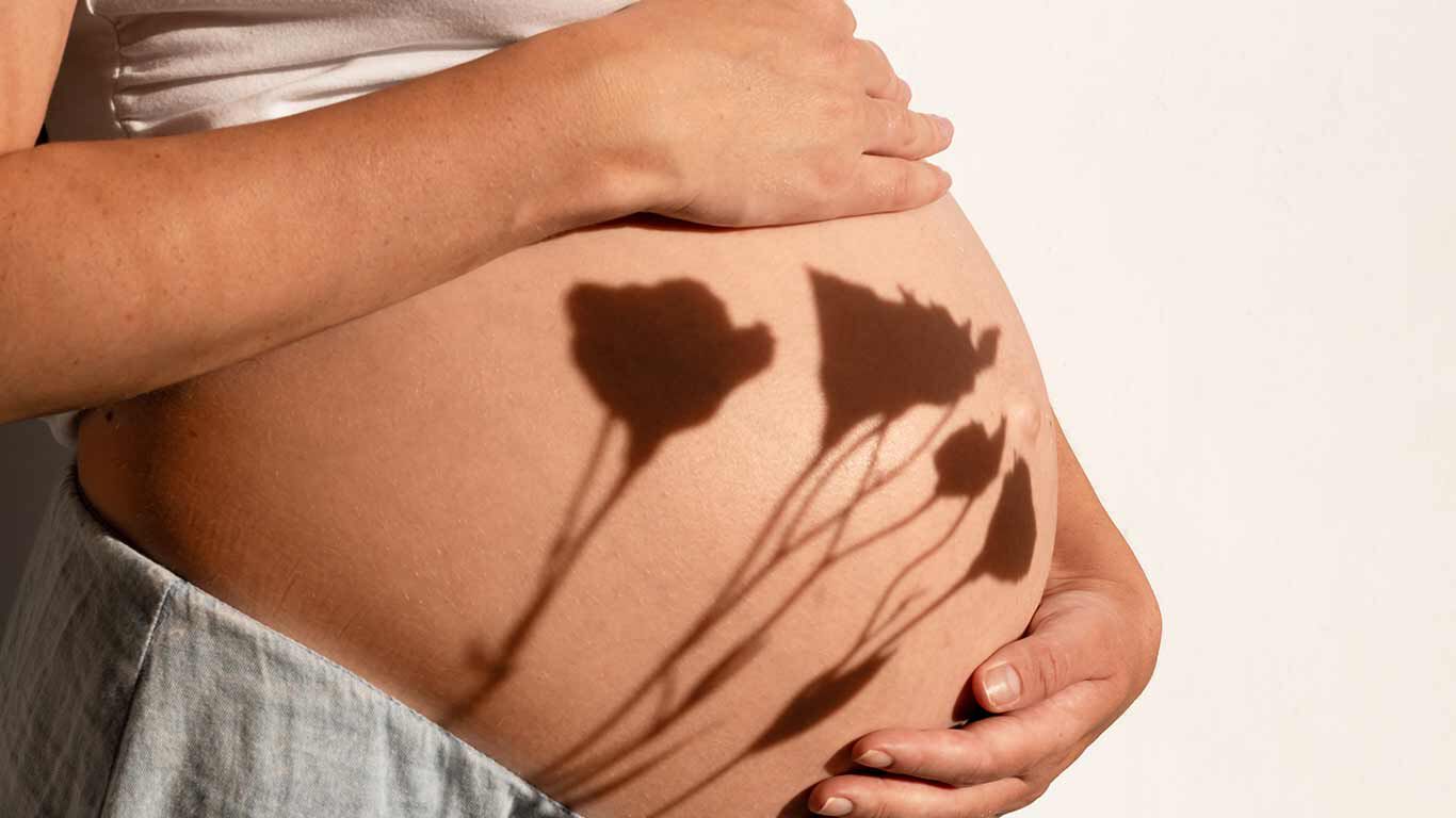 Babybauch mit Schatten von Pflanzen darauf. 