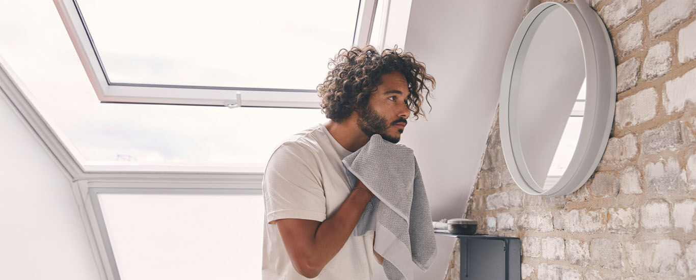 Mann  trocknet sich im Badezimmer mit einem Handtuch ab.