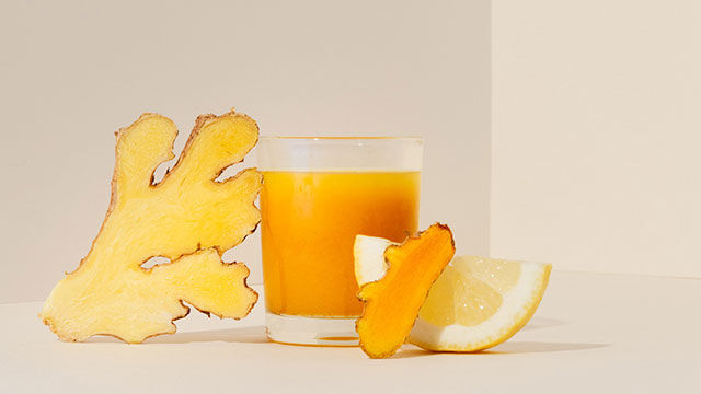 Gefülltes Glas mit Ingwer-Shot. Zutaten daneben.