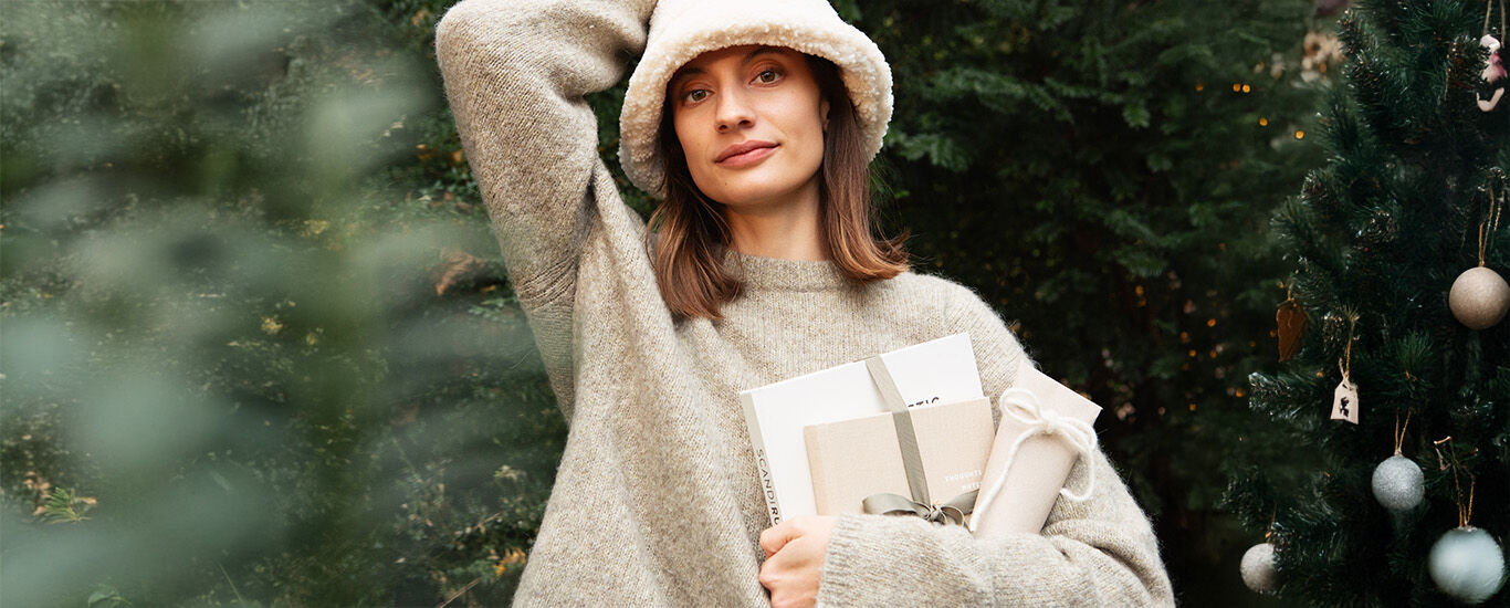 Finde das passende Geschenk Frau sitzt auf Sofa und packt Geschenk ein.