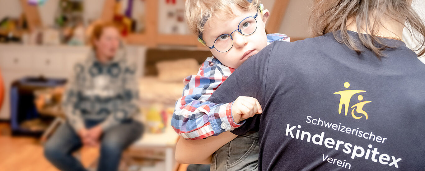 Erwachsene Frau mit Kinderspitex Shirt trägt Kind