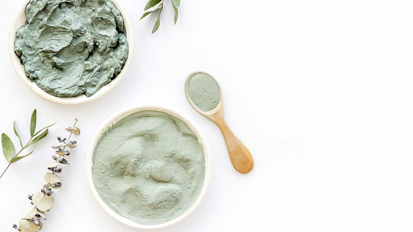 Flatlay von grüner Heilerde auf weißem Hintergrund.