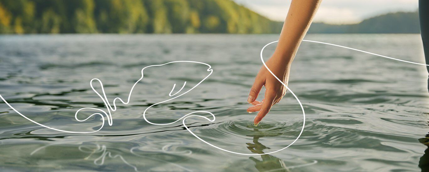 Eine Hand berührt das Wasser eines Sees, aus dem ein illustrierter Fisch springt