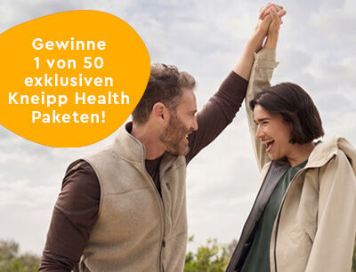 L&auml;chelnde Frau die an einer weissen Bl&uuml;te riecht.