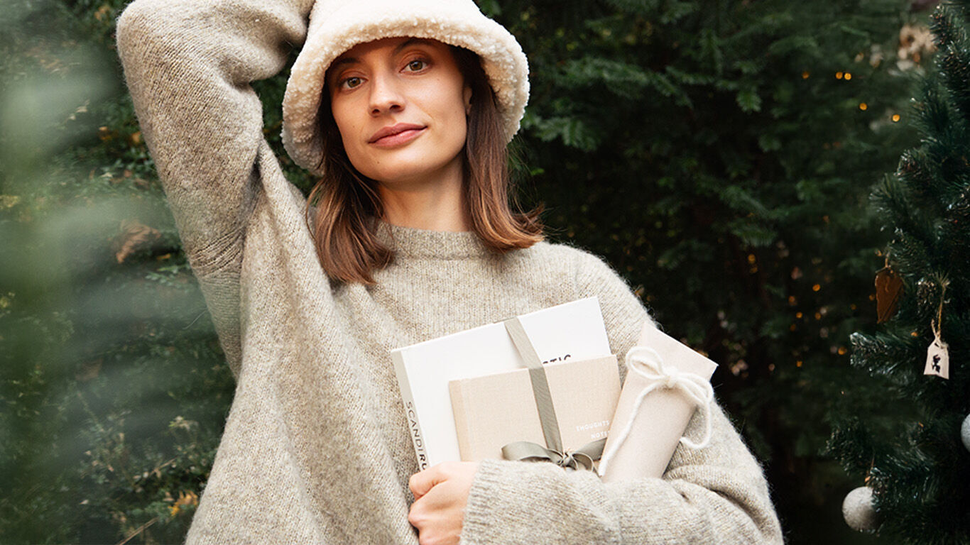 Finde das passende Geschenk Frau sitzt auf Sofa und packt Geschenk ein.