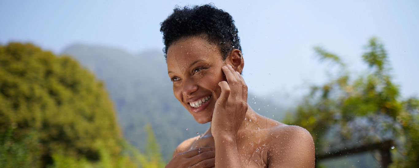 Frau genießt kühle Dusche im Freien.