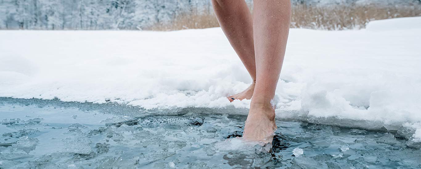 Gros plan sur des jambes qui entrent dans de l'eau glacée.