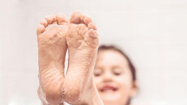 Mädchen streckt Füße aus der Badewanne.