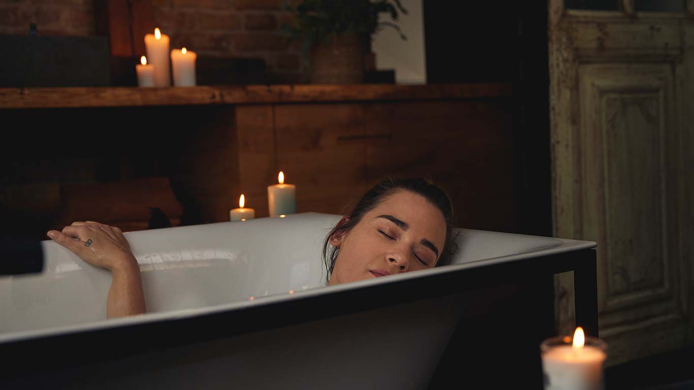 Frau liegt abends in der Badewanne