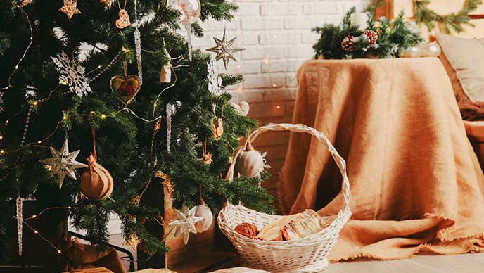 Geschmückter Weihnachtsbaum, daneben ein Holzkorb mit Geschenken.