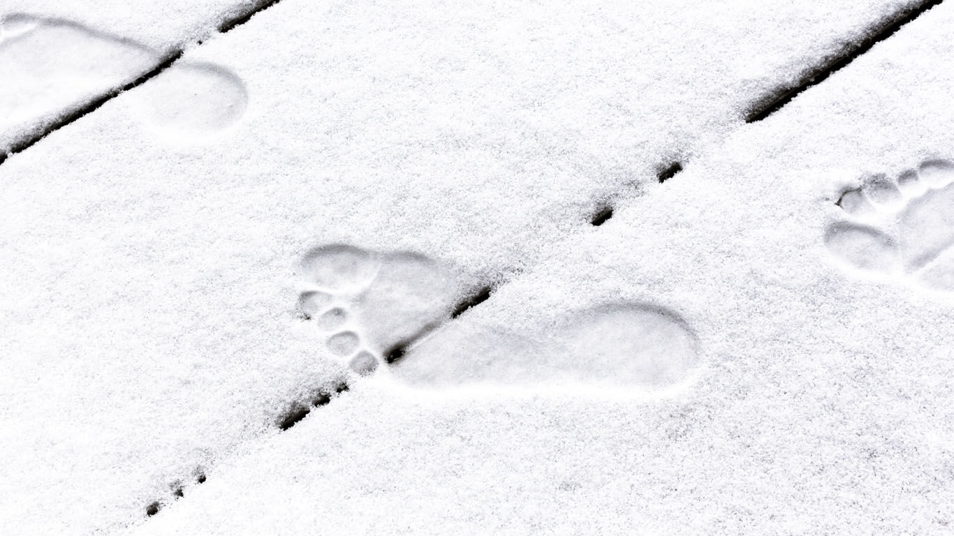 Schneebedeckter Boden, in dem man Abdrücke von Füßen erkennen kann.