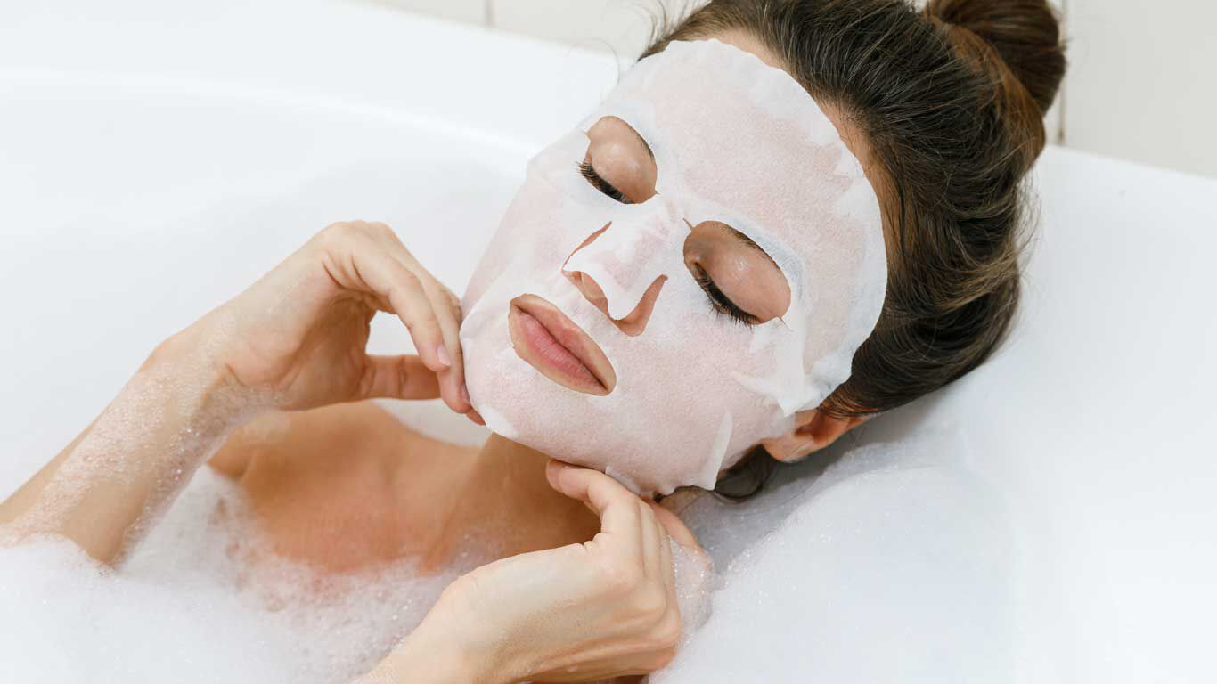 Femme se détend avec le masque en tissu Chill Out dans la baignoire