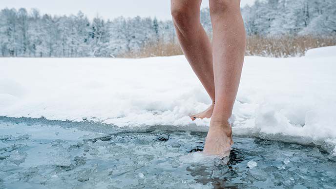 Gros plan sur des jambes qui entrent dans de l'eau glacée.