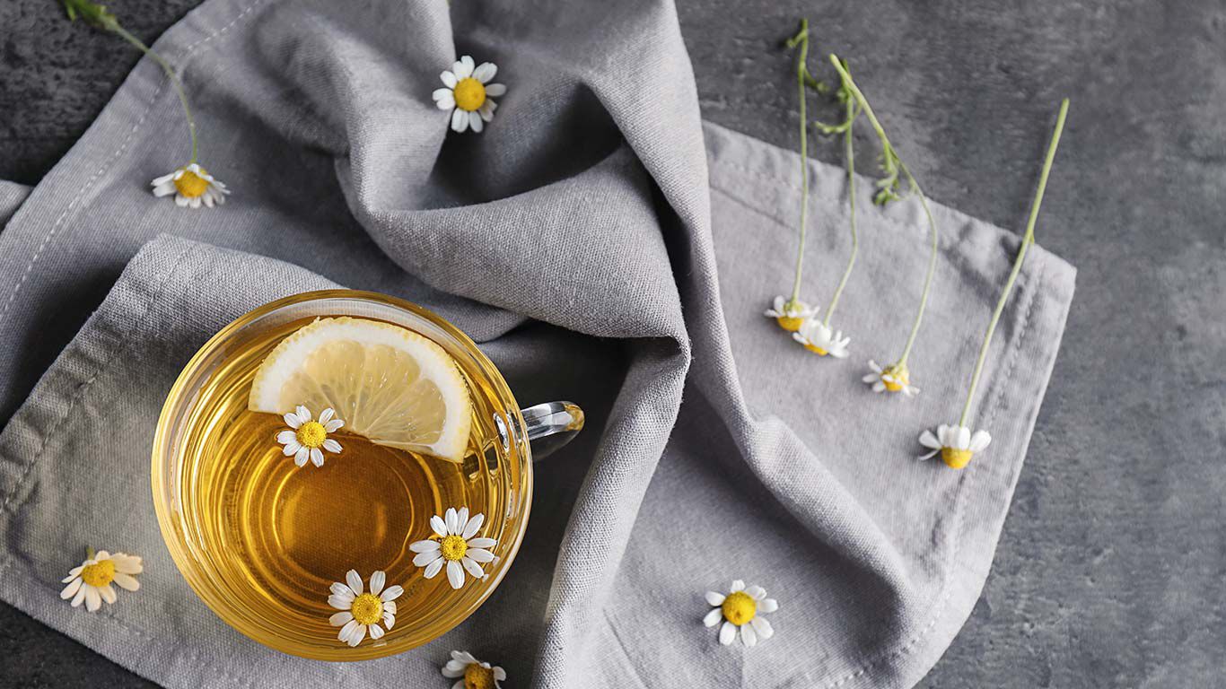 Thé à la camomille dans un verre à thé posé sur un tissu gris.