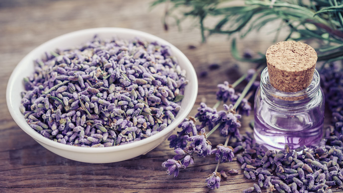 Getrockneter Lavendel neben einem Glas voller Lavendelöl.