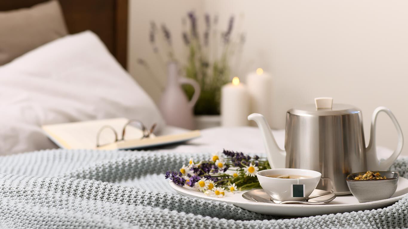 Teekanne und Tasse stehen auf dem Bett