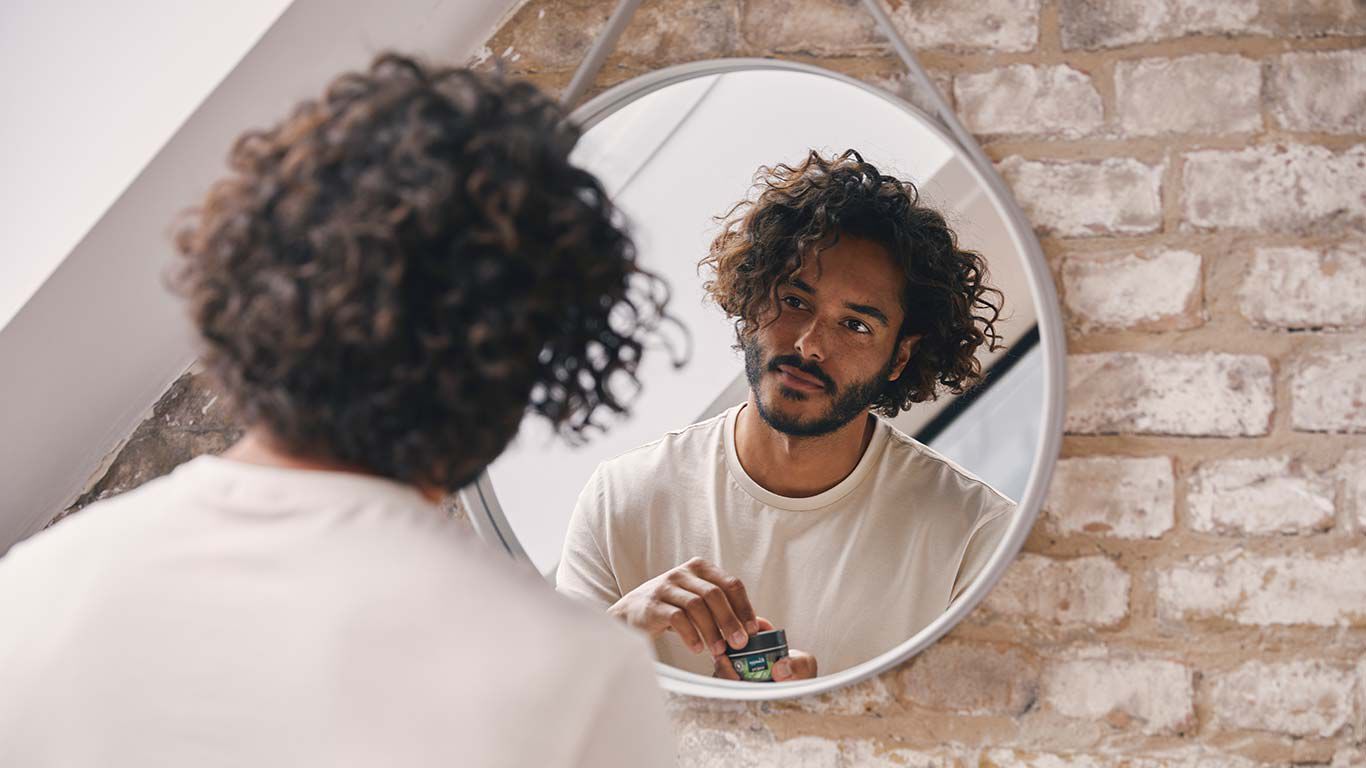 Un homme se tient devant le miroir dans la salle de bain et se regarde.