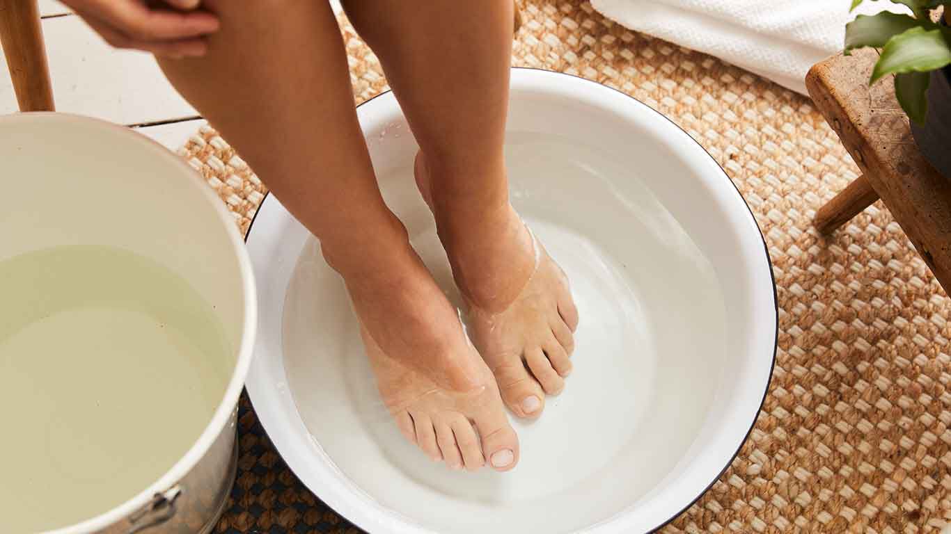 Bain de pieds alterné : les pieds dans une bassine d'eau froide. À côté, un seau d'eau chaude.