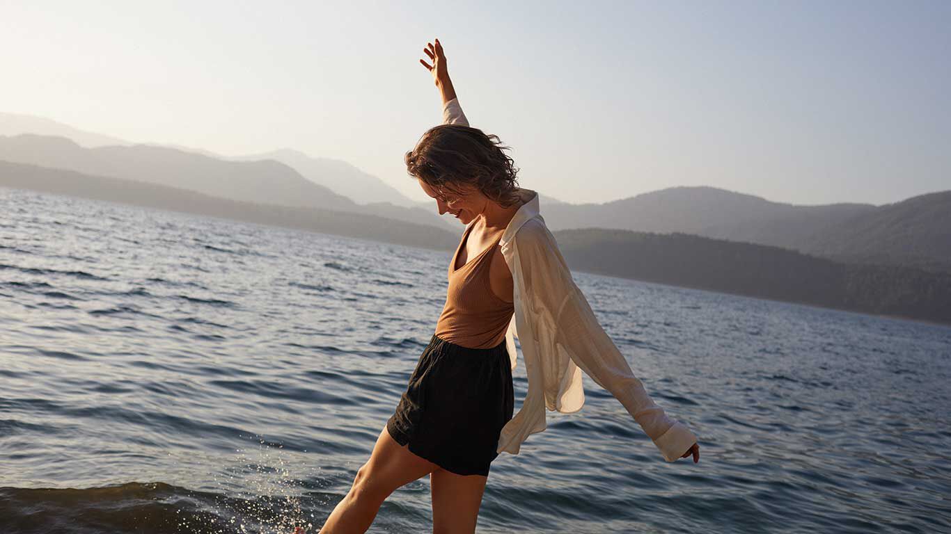 Frau genießt das Leben und Tanzt vor dem Meer.