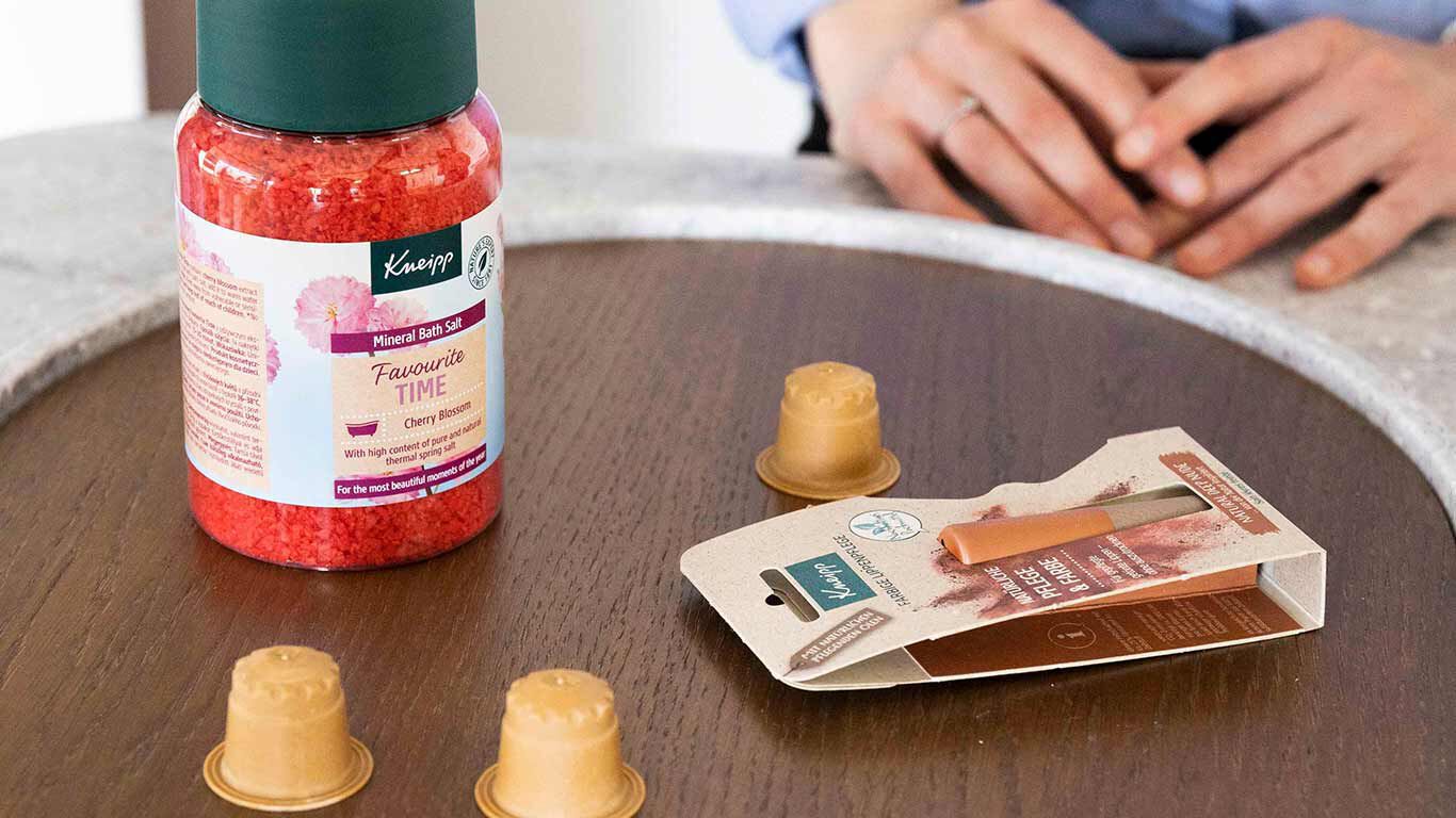 Des capsules de café Rezemo durables et un baume à lèvres Kneipp durable sur une table.