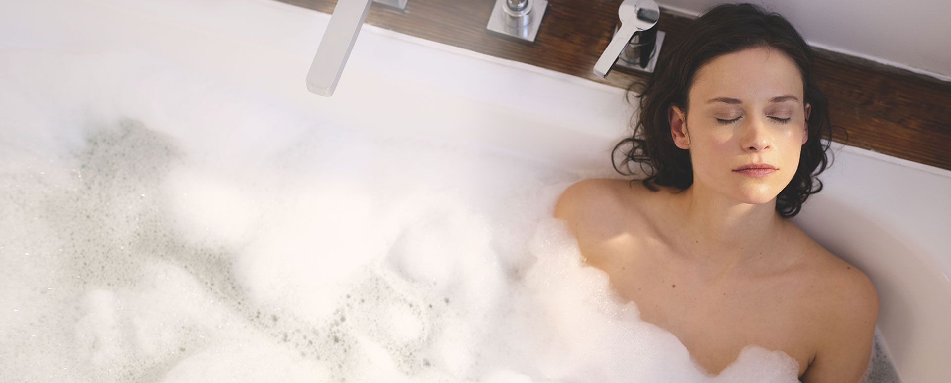 Femme les yeux ferm&eacute;s dans une baignoire remplie de mousse