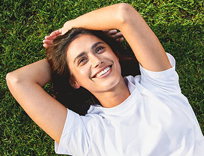 Newsletter Femme allongée sur le dos dans une prairie en riant