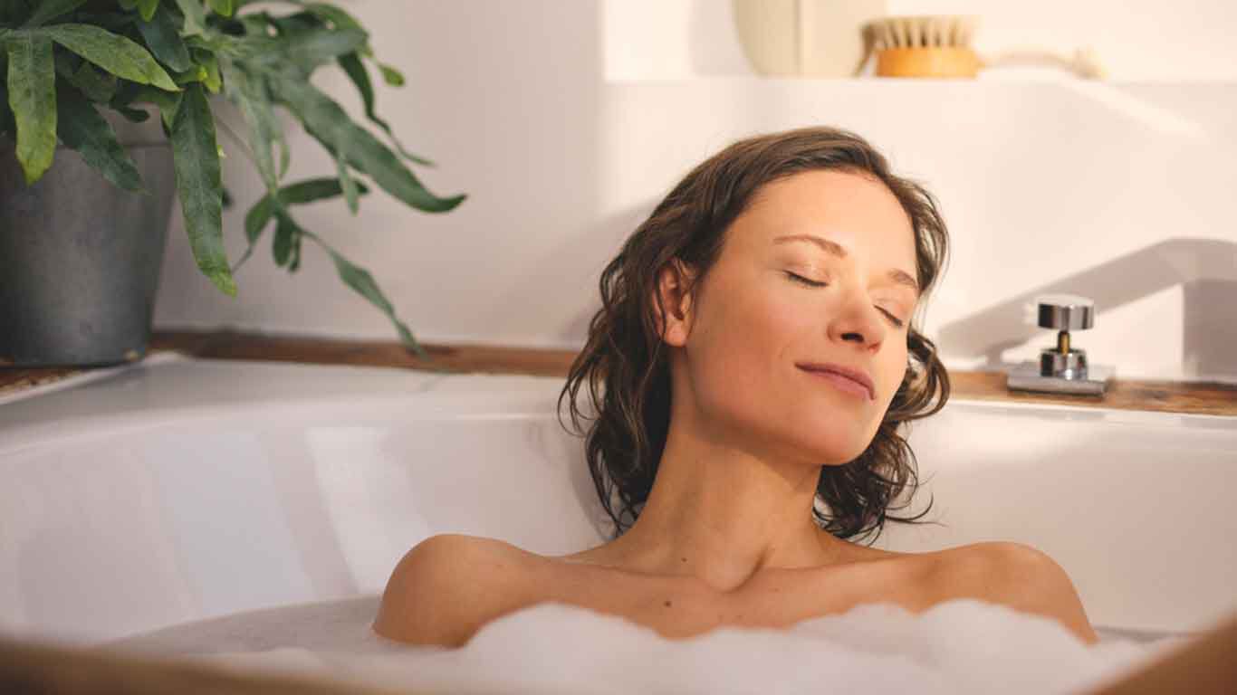 Une femme se d&eacute;tend dans une baignoire remplie de mousse. 