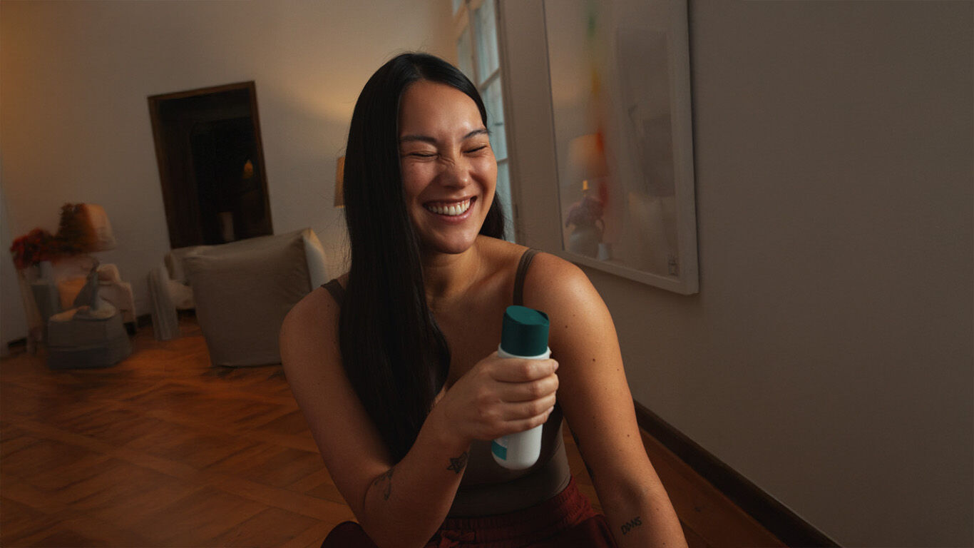 Femme avec du gel douche dans la main, qui rit