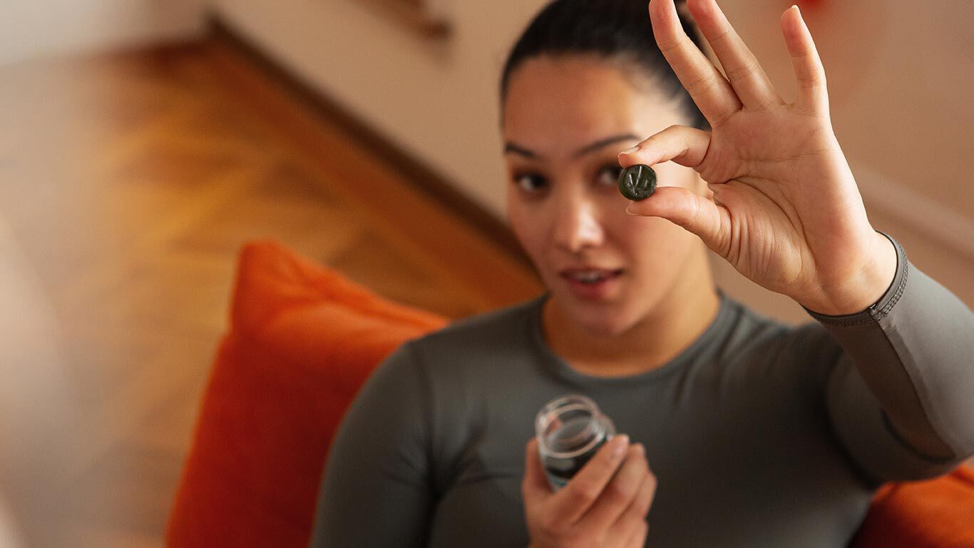 Femme aux cheveux noirs tenant une gomme Kneipp devant la caméra