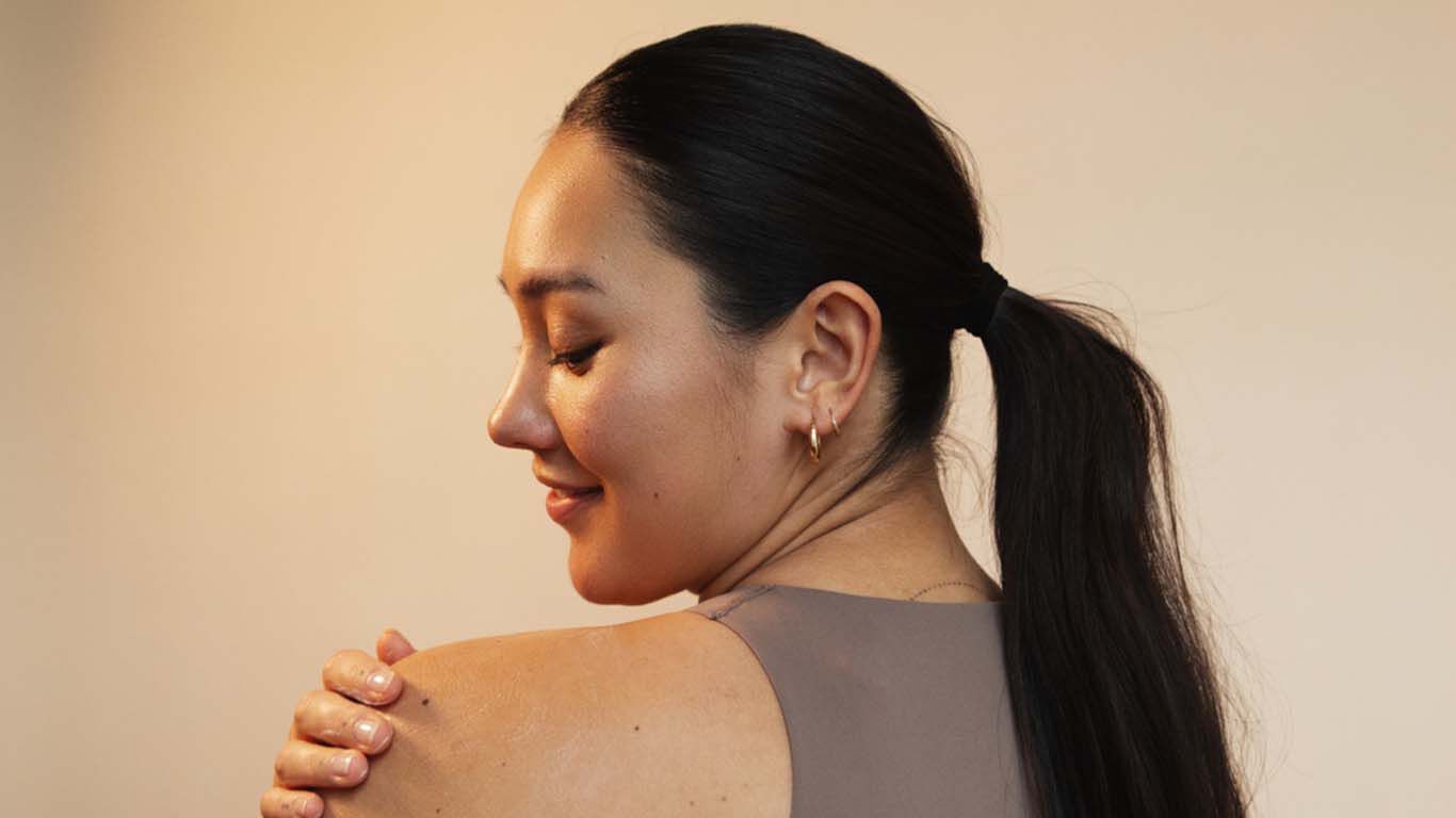 Femme aux cheveux noirs, regardant par-dessus son épaule gauche et se tenant par l'épaule