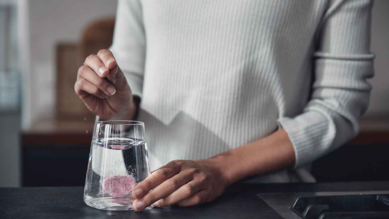 La pastille pétillante est jetée dans un verre d'eau. 