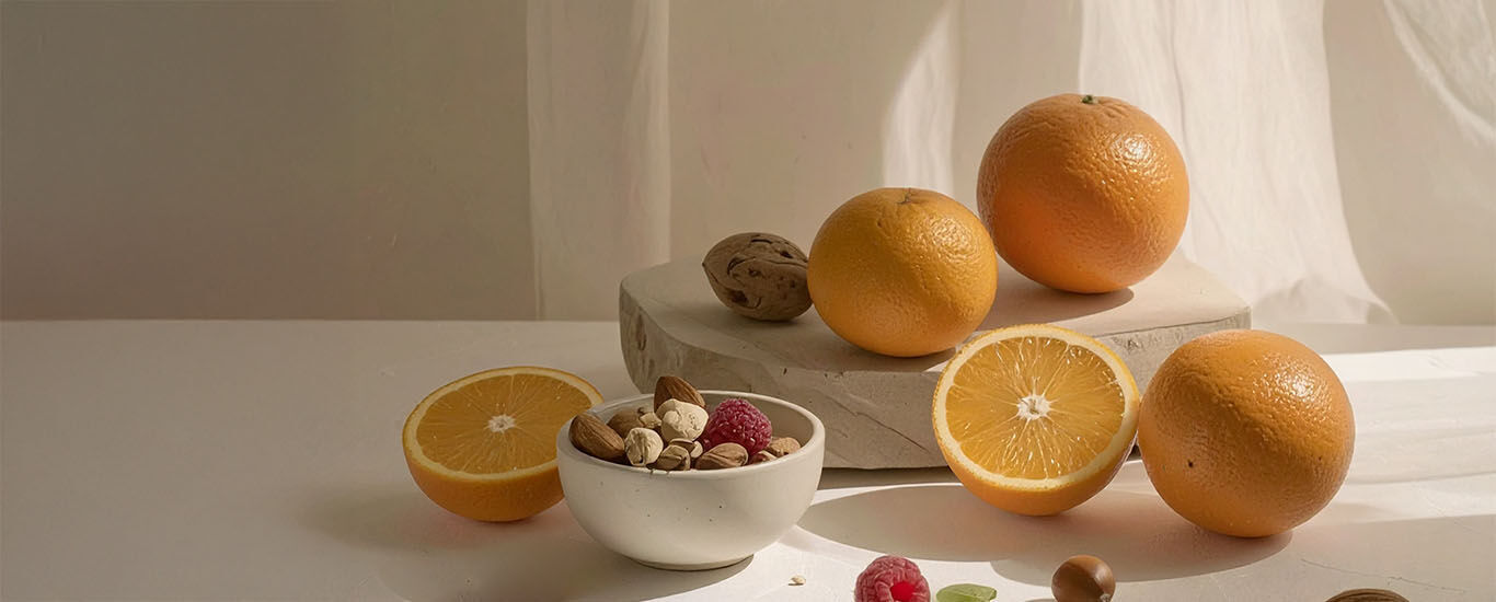 Des oranges fra&icirc;ches avec des noix et des baies sur une d&eacute;coration en pierre naturelle claire - un arrangement alimentaire sain.