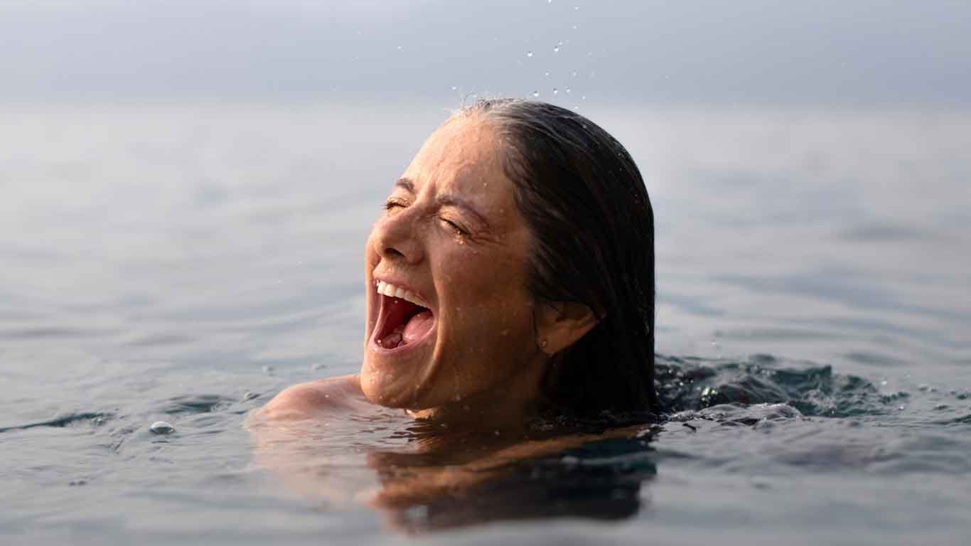 Žena se koupe v moři a křič&iacute; radost&iacute;.