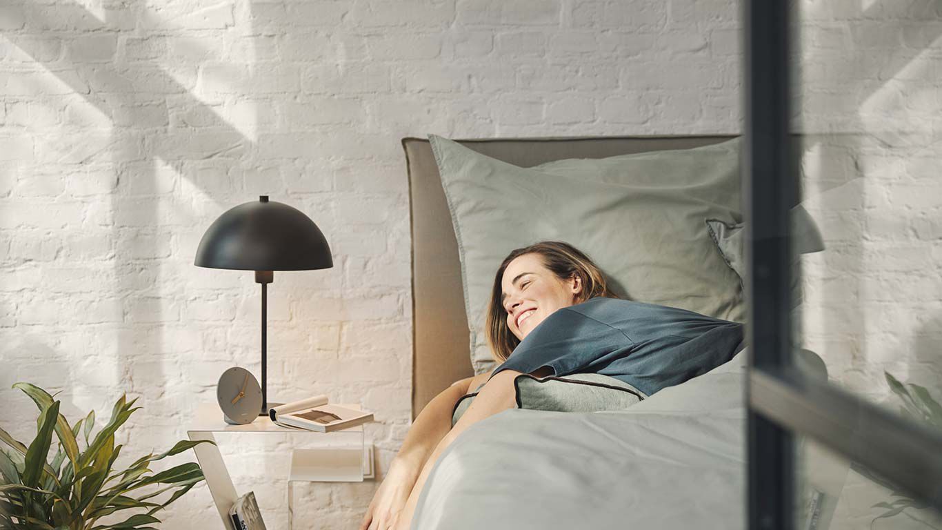 Žena spokojeně lež&iacute;c&iacute; v posteli.