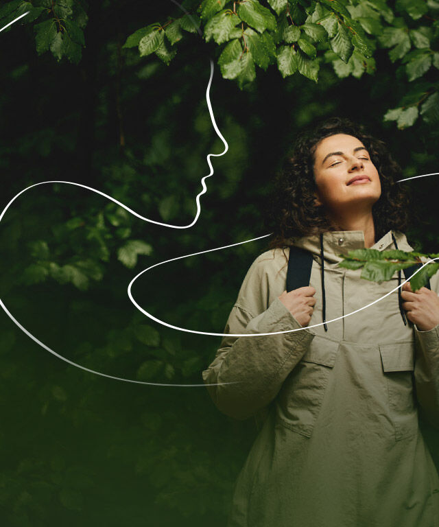 Una mujer mira al bosque y al cielo y disfruta de la naturaleza. Una ilustración blanca a modo de línea recorre el cuadro y simboliza el rostro de una mujer de perfil.