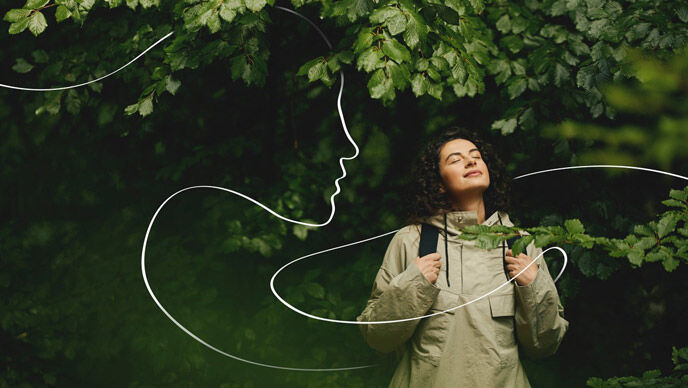 Una mujer mira al bosque y al cielo y disfruta de la naturaleza. Una ilustración blanca a modo de línea recorre el cuadro y simboliza el rostro de una mujer de perfil.