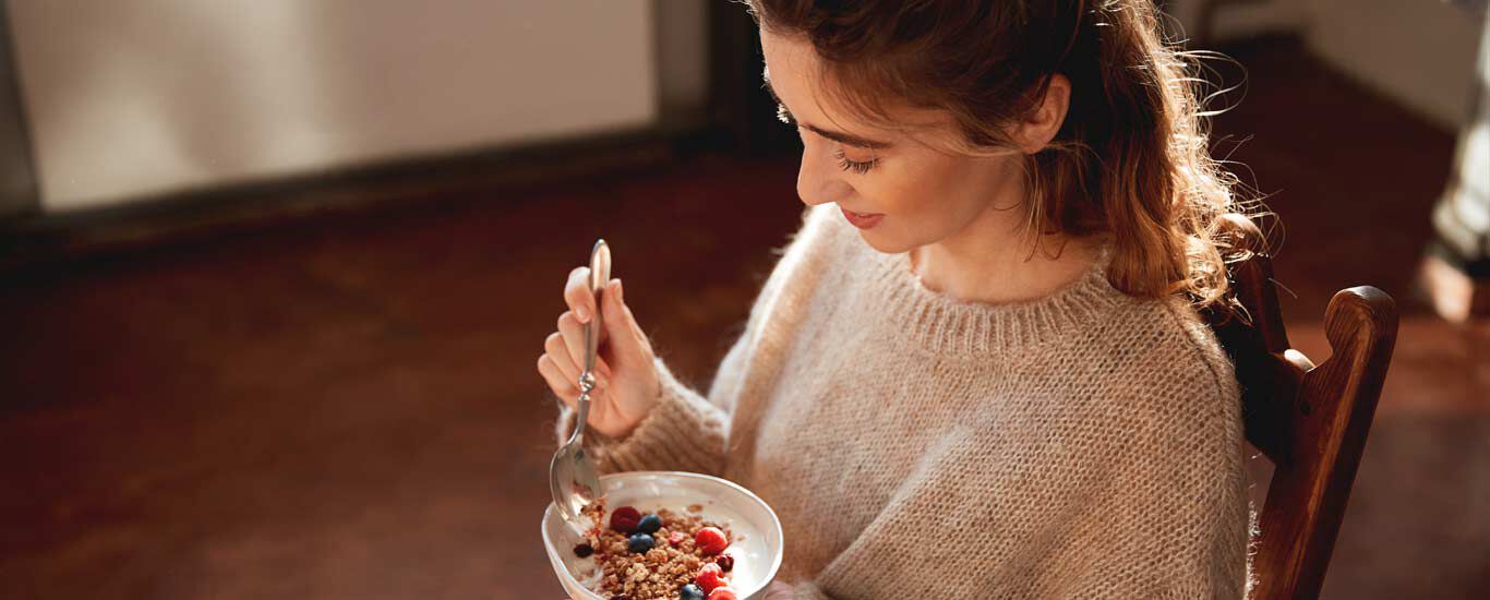Mujer comiendo cereales con bayas.