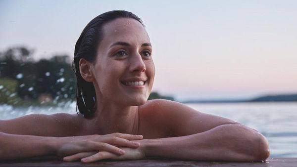 Mujer apoyada en un muelle en el agua